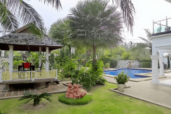 Very nice Pool Villa near Mabprachan lake in best quality and has been well cared by their owners, this quaility property is renovated in 2012. The ground-floors generous living- and dining-area widely opens to the covered-terrace, the pool and gardens and the kitchen is made out of massive teak and so are quite all the built-in. This kitchen is equipped with all the appliances that make cooking joyful and easy plus there is a well-equipped Thai kitchen and also have a laundry room there as well. Outdoors, you get a lavish pool of nearly 100 m2 that is salt-chlorinated also offering an extra Jacuzzi pool plus a waterfall feature. Then the fish pond with beautiful Koi’s swimming. The juicy lawns are easy to maintain as a timer-controlled sprinkler system is in place. The property is surrounded by an attractive natural stone wall. You would access the covered double-carport through a remote-controlled stainless gate. Here we are with the quality features: The whole house is built double cavity and the roof is ventilated. There is ADSL-Internet with Wi-Fi signal all over the property. There are 3 underground freshwater-tanks that are supplied by either your own ground-water or water from the public. There is atmospheric garden lighting and a sound-system installed in the ceilings of the living-area and the terrace. Hot (not just warm) water comes from a central boiler, there are zinc-coated gutters and also an alarm-system installed. A drainage system leads the rain-water underneath the nearby road. All the furniture and equipment seen on the photos stay there. The pool and garden maintenance is included in the rental price.